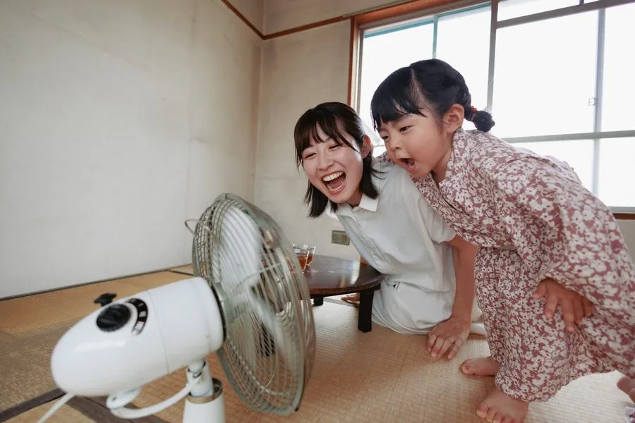 扇風機の前で、声を出して笑う女性と女の子