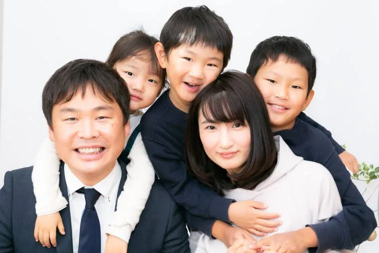家族5人が肩を寄せ合って笑っている集合写真
