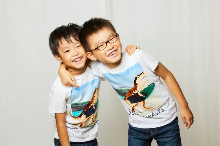 Tシャツを着た兄弟が肩を組んで笑っている