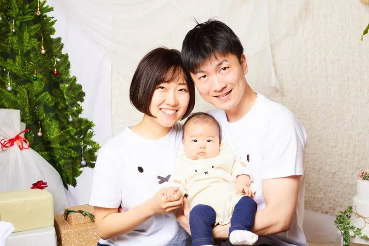 クリスマスの飾りの前で赤ちゃんを抱く両親