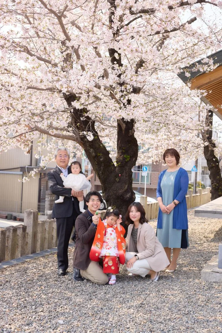 桜の木の下に並ぶ、祖父母を含めた家族全員