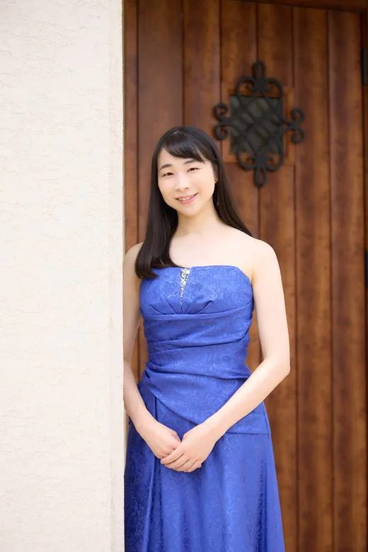 木の扉の前に立つ、青いドレスの女性のプロフィール写真